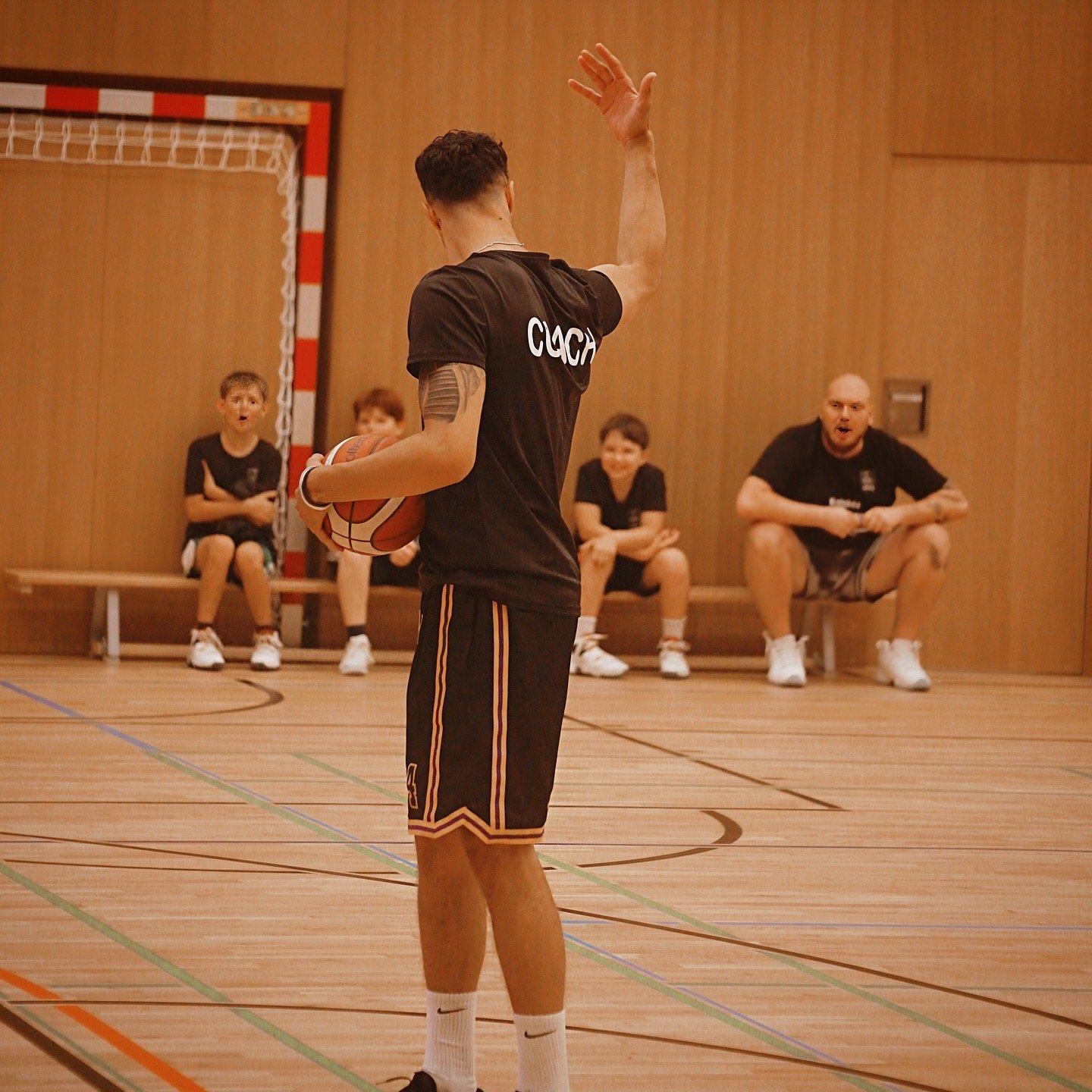 Trainer erklärt Kindern eine Übung in der Halle